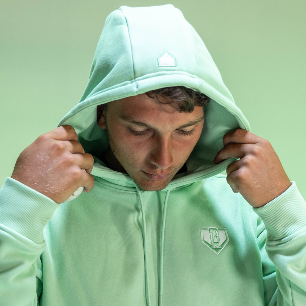 Person wearing a light green hoodie with a BL101 logo on a light green background