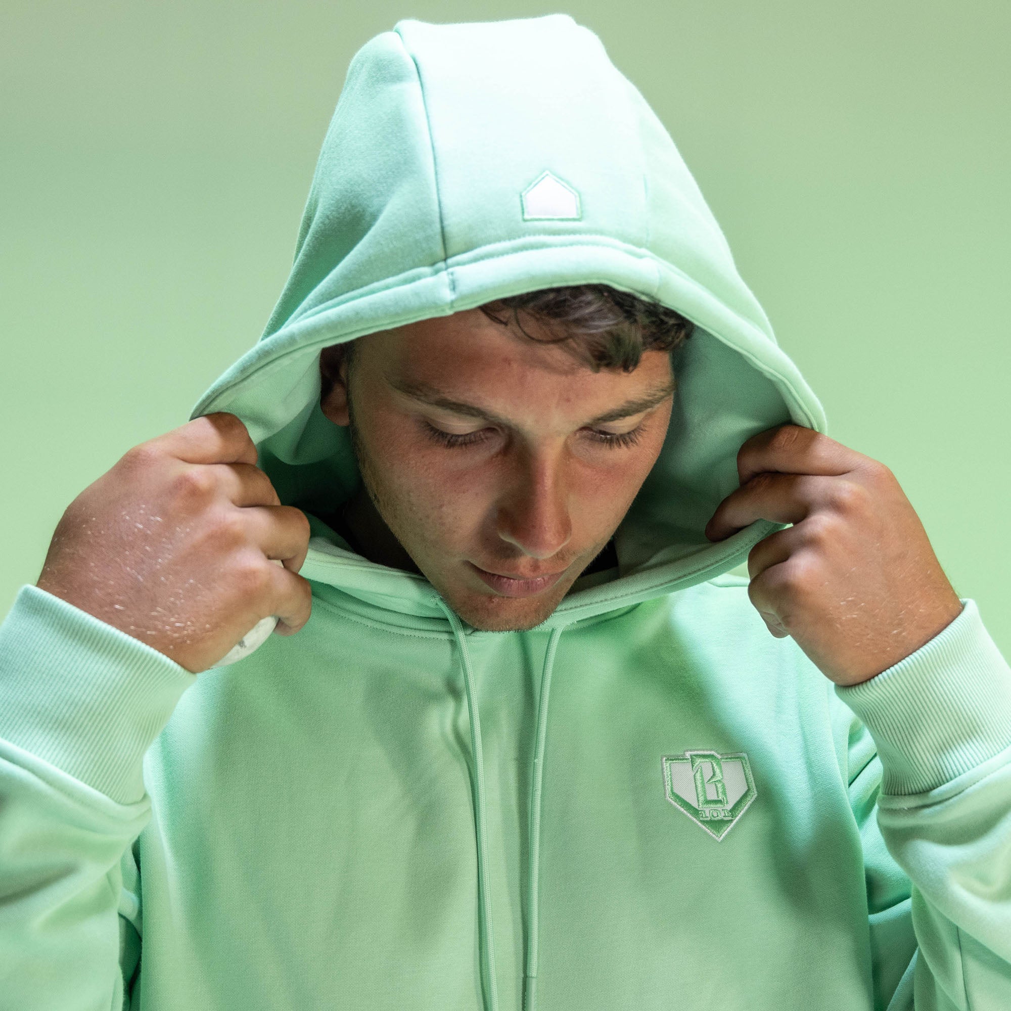 Person wearing a light green hoodie with a BL101 logo on a light green background