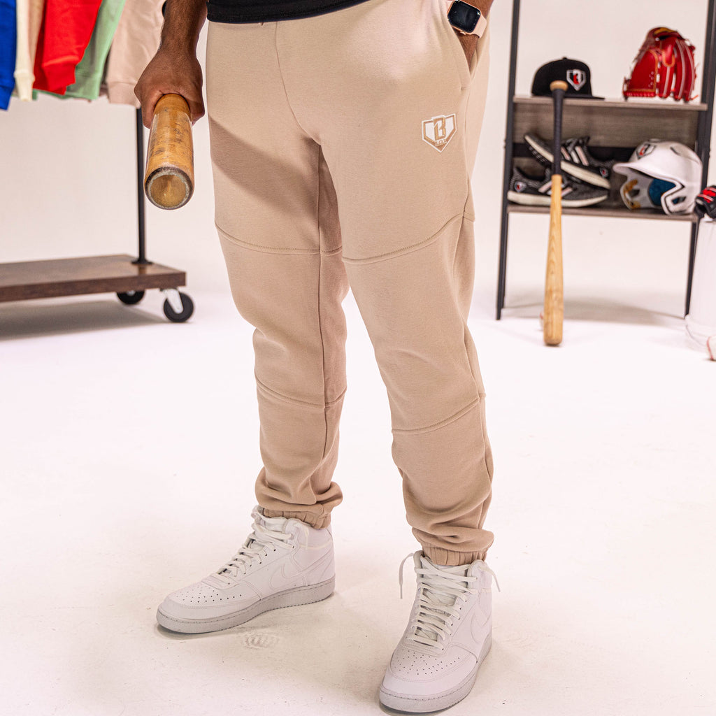 Person wearing beige sweatpants with a white BL101 logo, standing in a room with sports equipment.