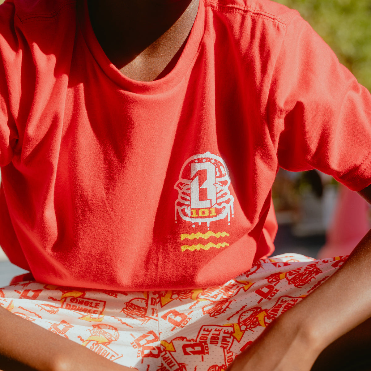 Youth model wearing youth graphic tee with "Burger" design