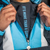 Person wearing a blue, white and black jacket with 'It's More Than A Game' text on the zipper.