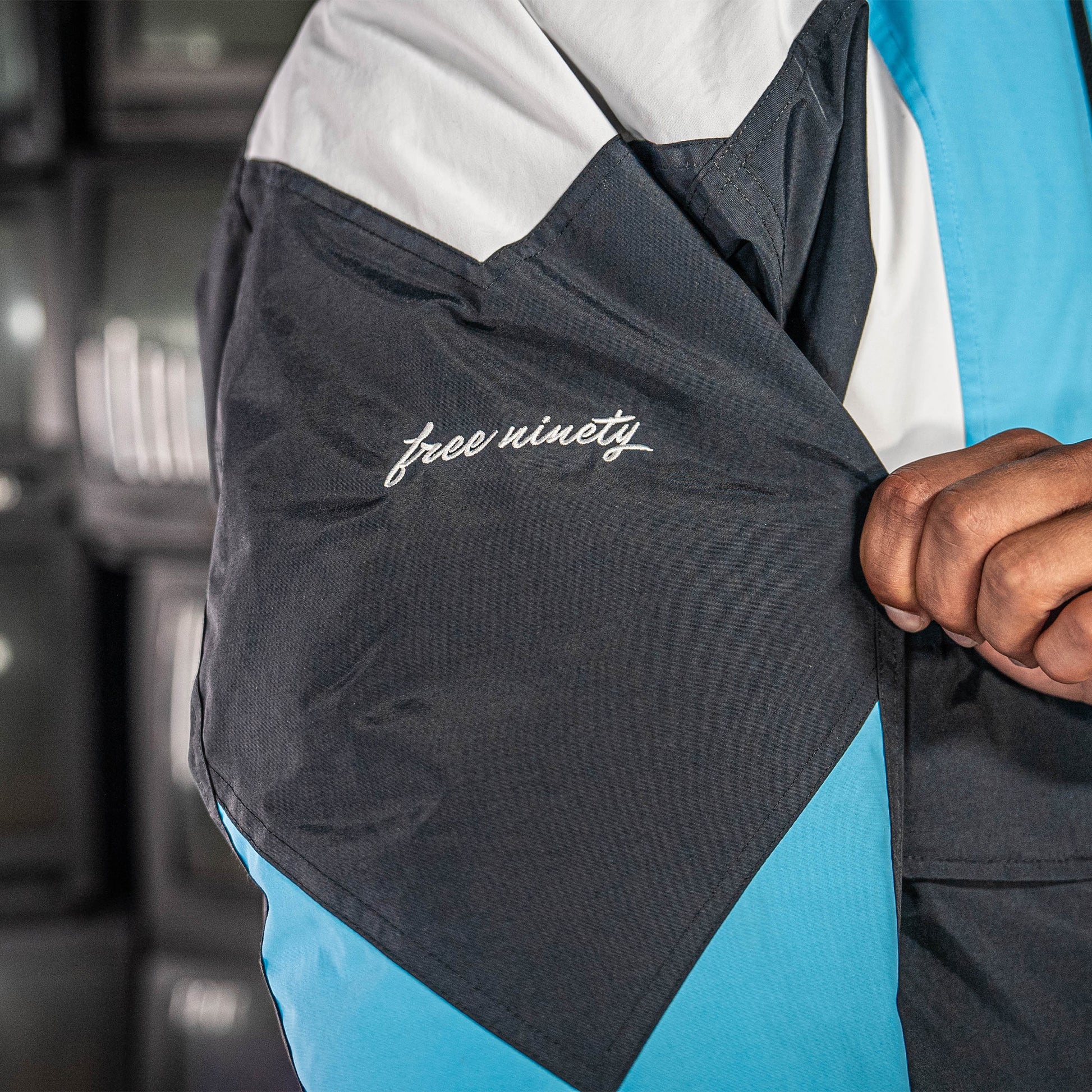 Close-up of a jacket with 'free ninety' branding on the sleeve on a blurred background