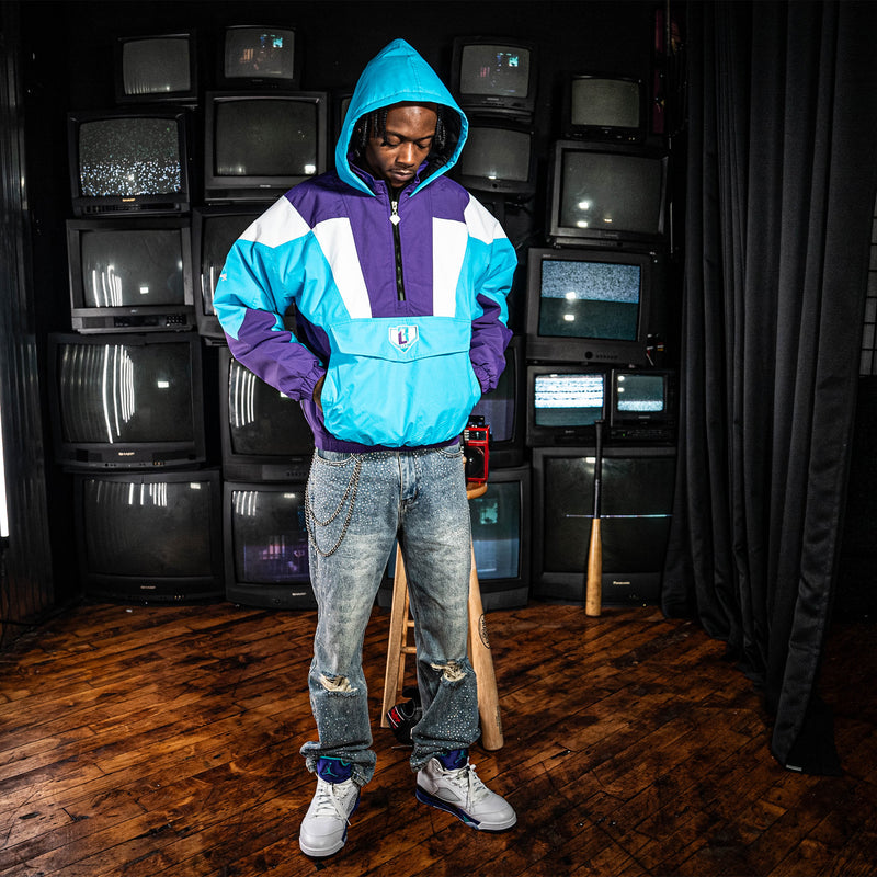 Person wearing a blue, purple and white jacket with a BL101 logo in a room with multiple vintage TVs.