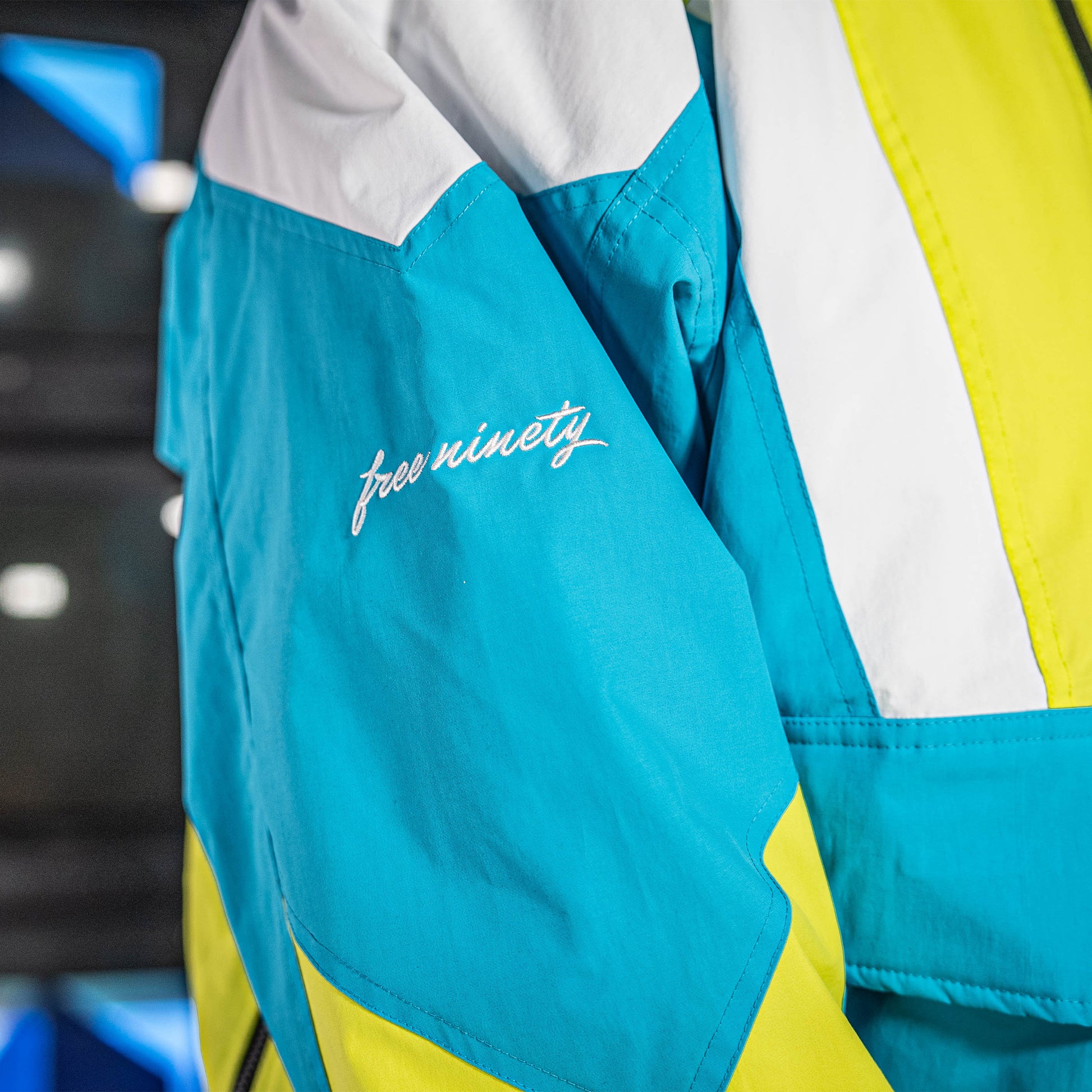 Blue, yellow and white jacket with 'free ninety' branding on a blurred background
