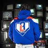 Person wearing a blue, red and white jacket with BL101 logo in front of vintage TVs.
