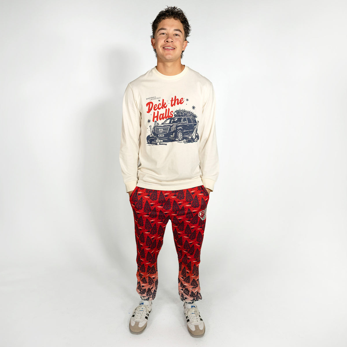 Adult model wearing white graphic tee with "Deck The Halls Long Sleeve" design