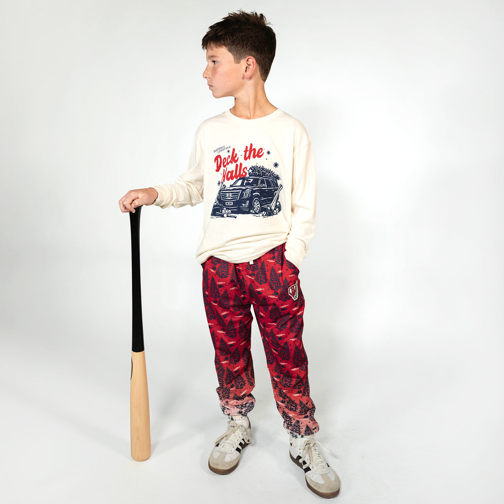 Youth model wearing white youth graphic tee with "Deck The Halls Long Sleeve" design