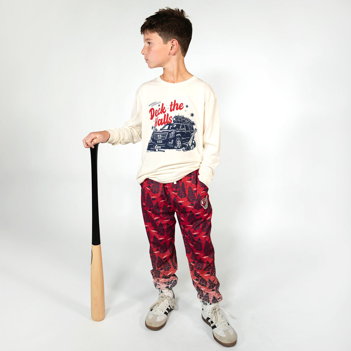 Youth model wearing white youth graphic tee with "Deck The Halls Long Sleeve" design