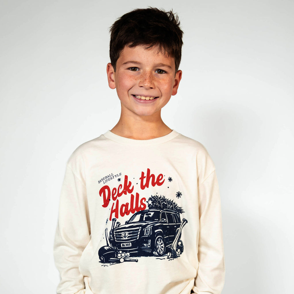 Youth model wearing white youth graphic tee with "Deck The Halls Long Sleeve" design