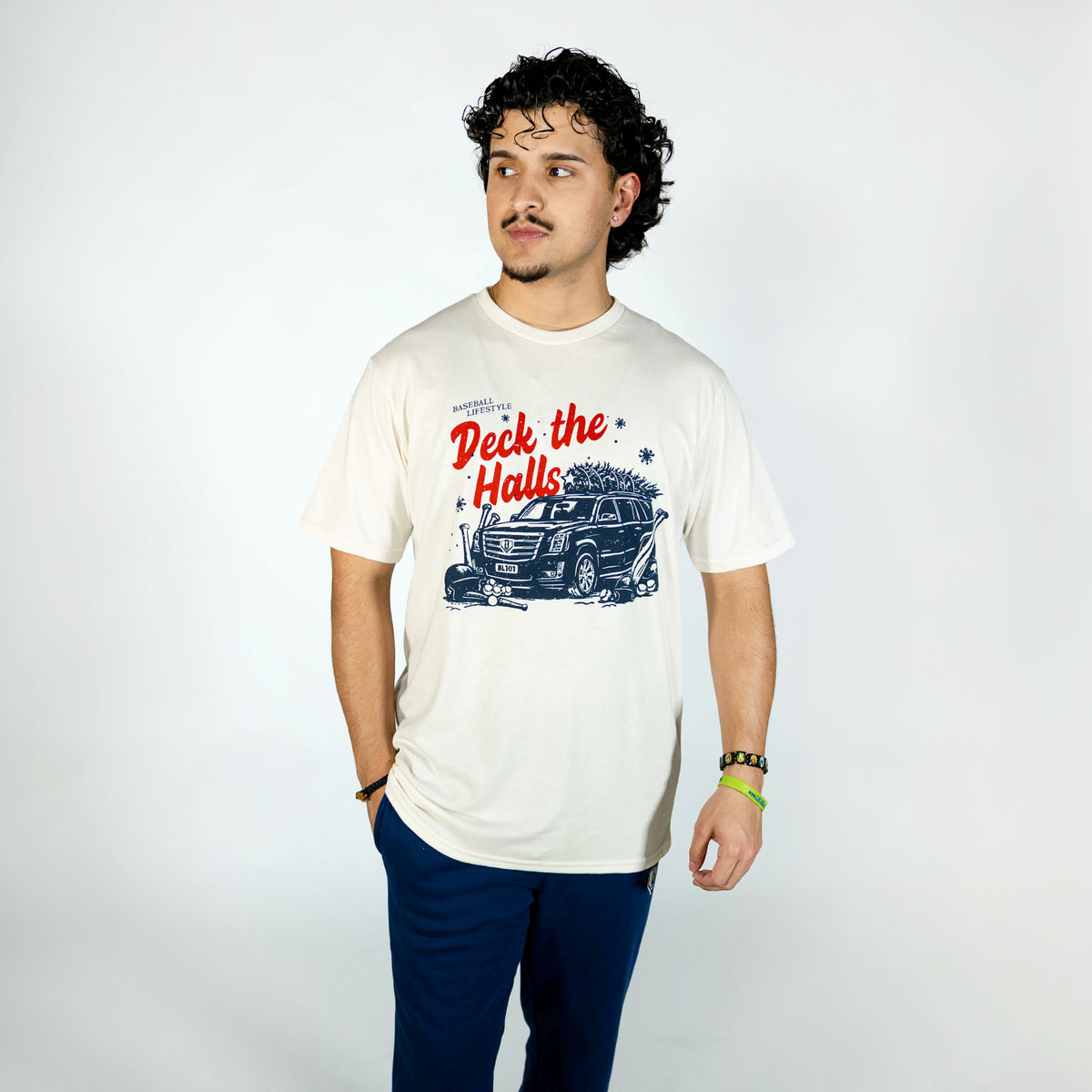 Adult model wearing white graphic tee with "Deck The Halls" design