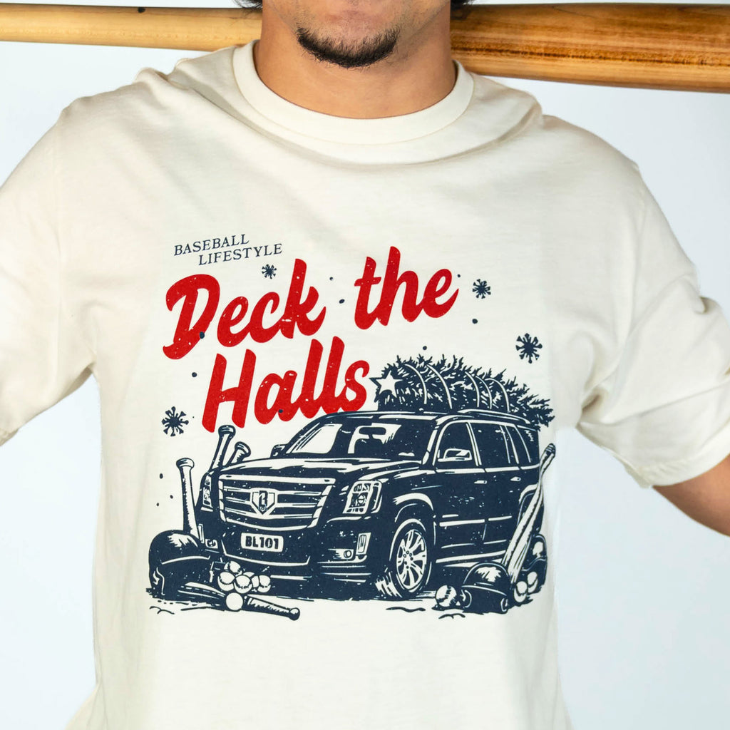 Adult model wearing white graphic tee with "Deck The Halls" design