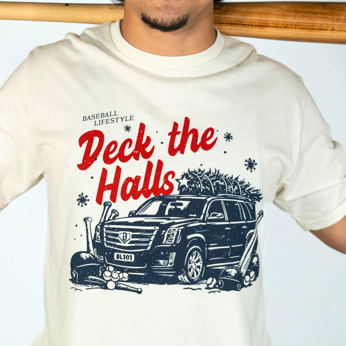 Adult model wearing white graphic tee with "Deck The Halls" design