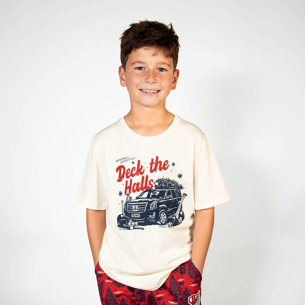 Youth model wearing white youth graphic tee with "Deck The Halls" design
