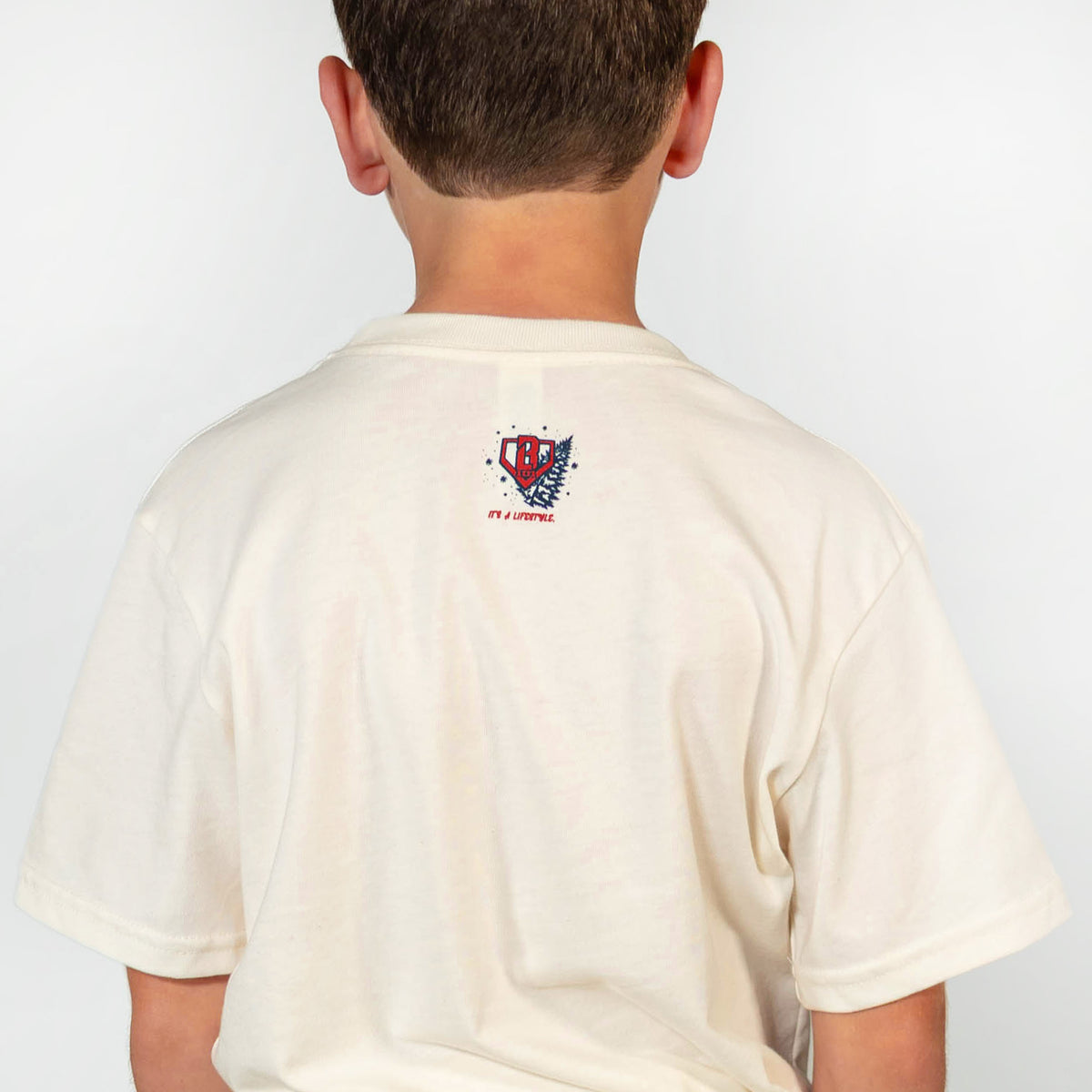 Youth model wearing white youth graphic tee with "Deck The Halls" design