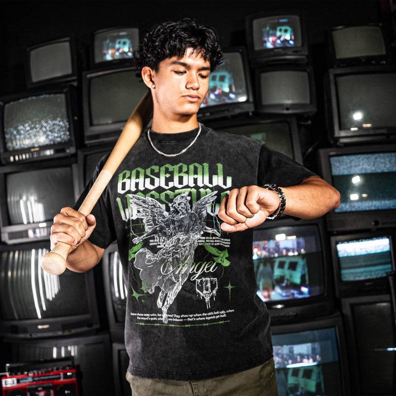Person wearing green and white graphic tee with text, holding a baseball bat in front of vintage televisions