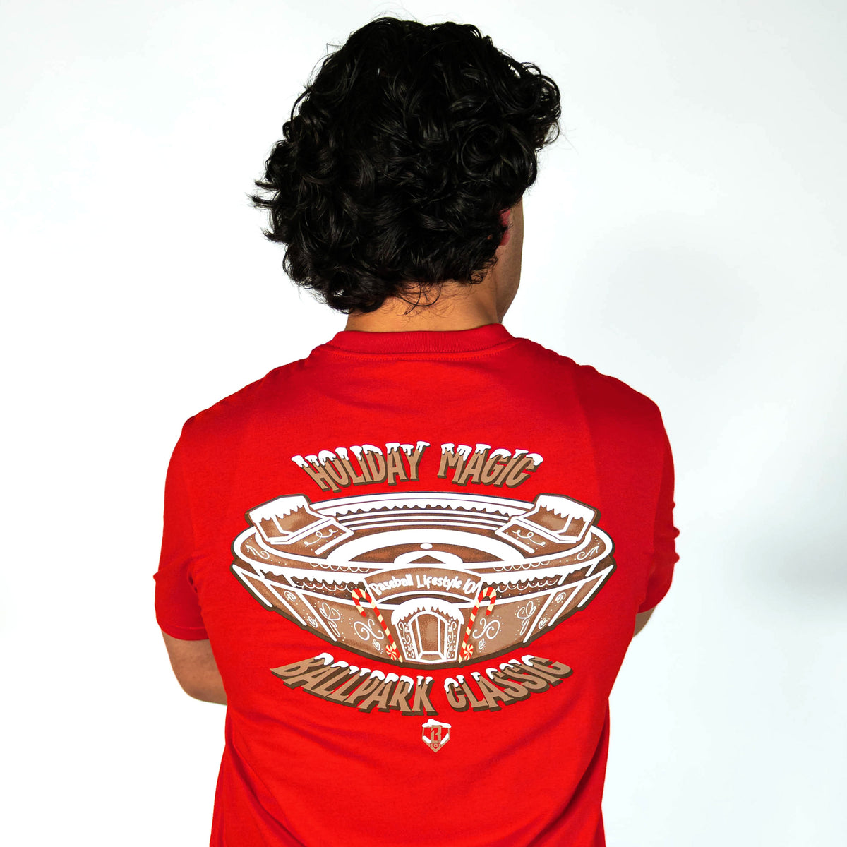 Adult model wearing red graphic tee with "Gingerbread Stadium" design
