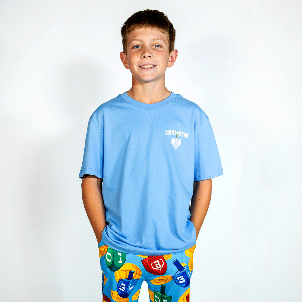 Youth model wearing blue youth graphic tee with "Glow Big" design