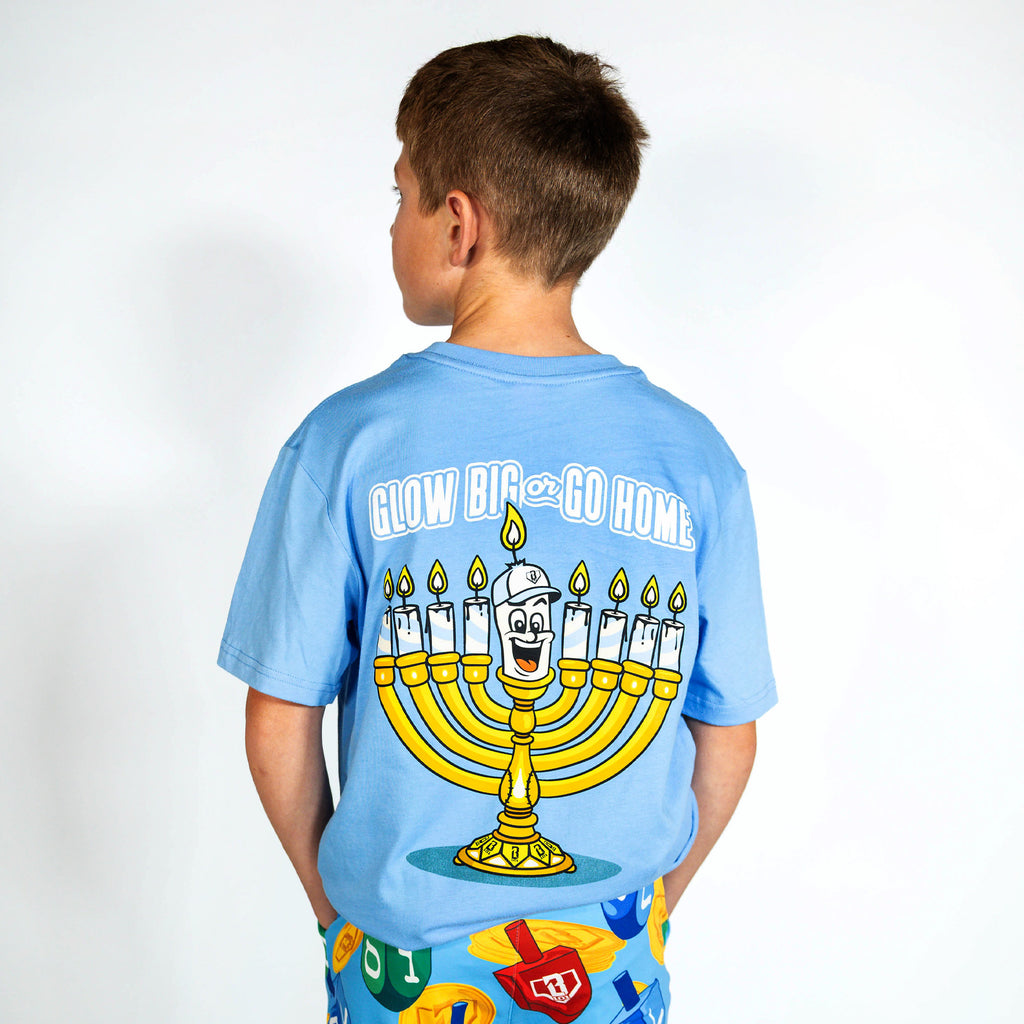 Youth model wearing blue youth graphic tee with "Glow Big" design