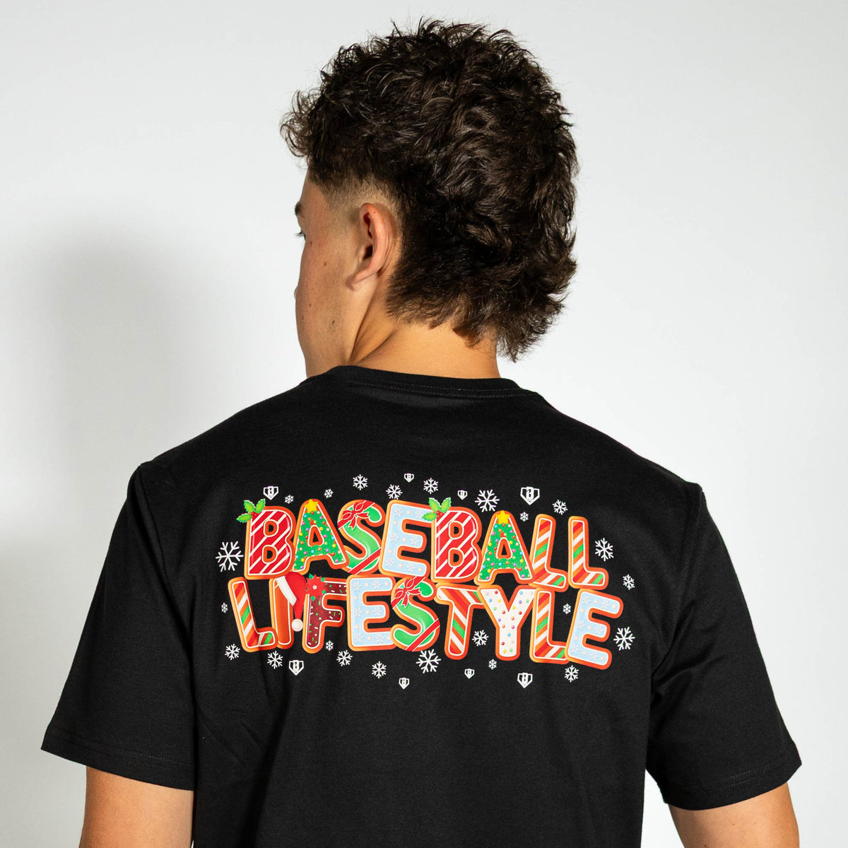 Adult model wearing black graphic tee with "Holiday Cookie" design