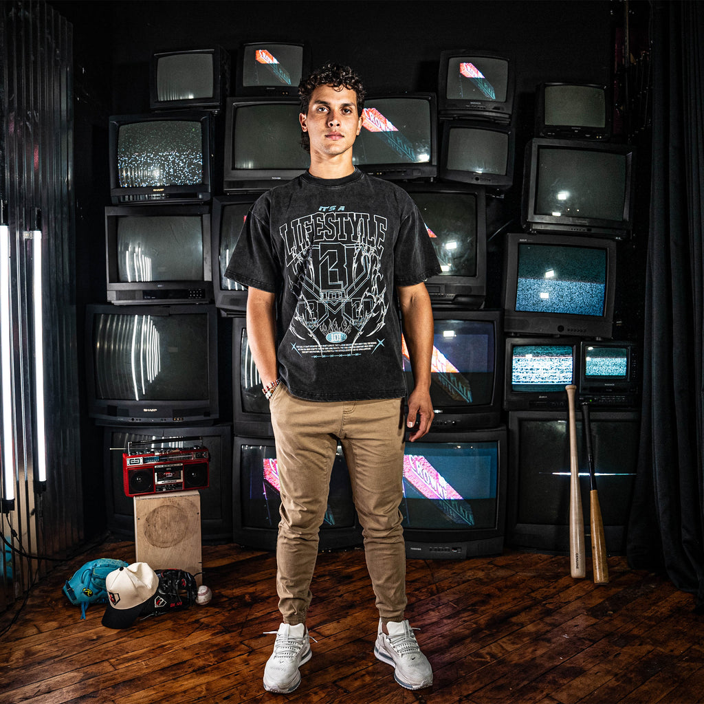 Person wearing a grey t-shirt with text standing in front of vintage TVs.