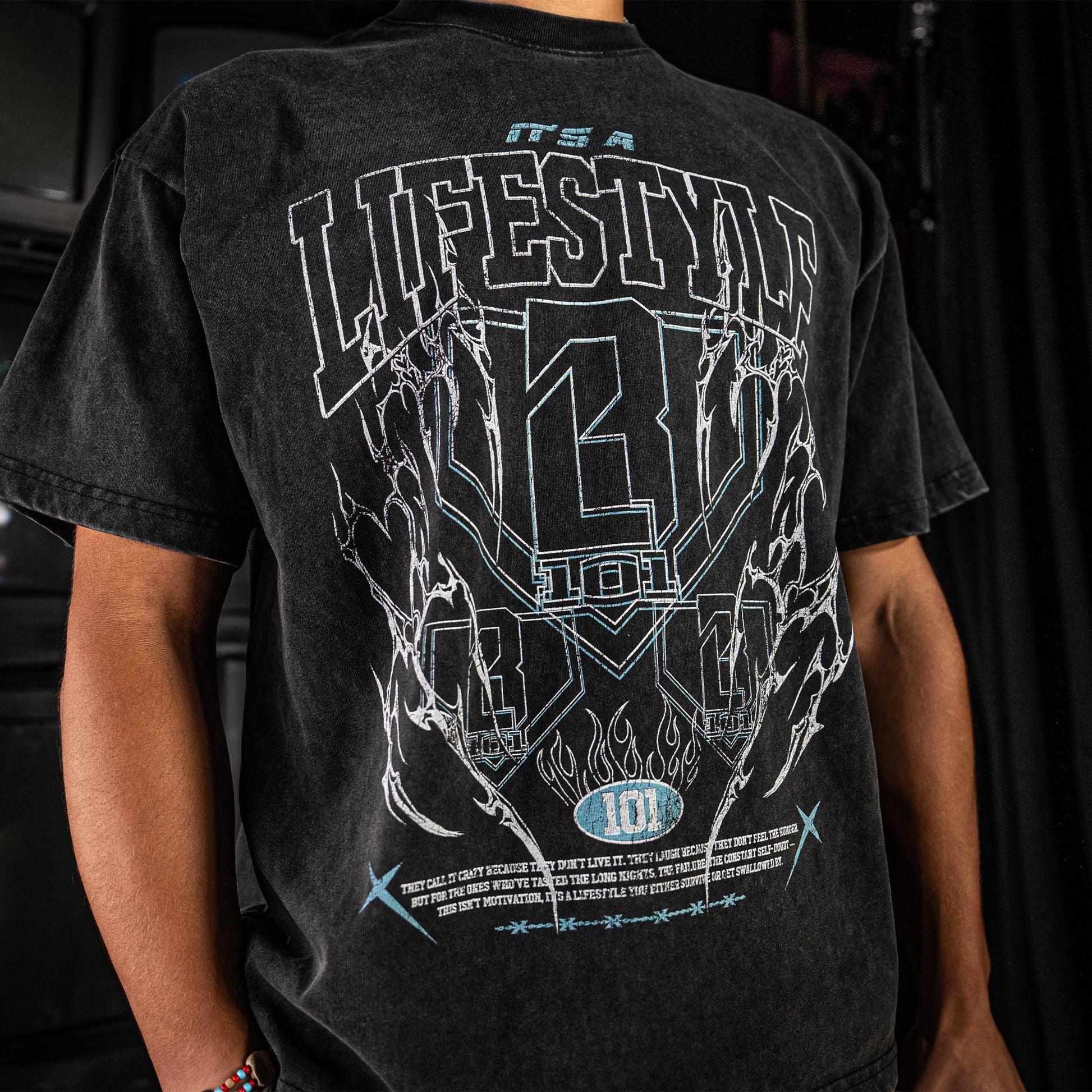 Grey t-shirt with white graphic design on the back, worn by a person.