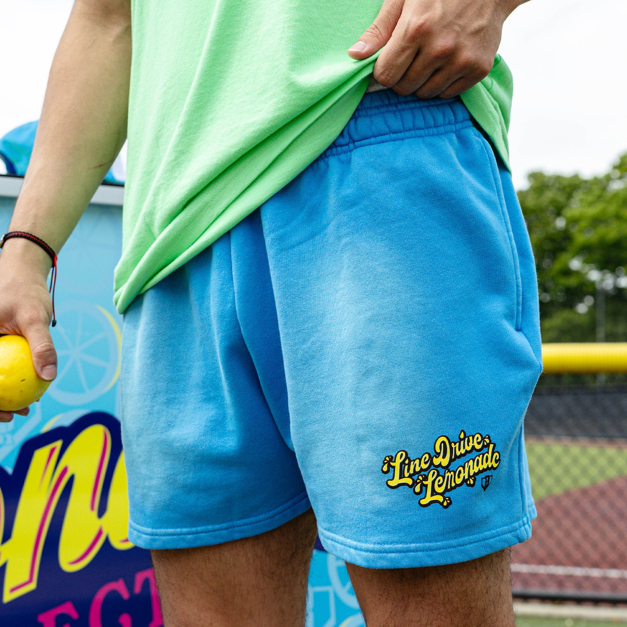 Adult model wearing blue shorts with "Lemonade Cup" design