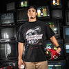 Man wearing a black t-shirt with graphic design and 'Baseball Lifestyle' text in front of vintage televisions
