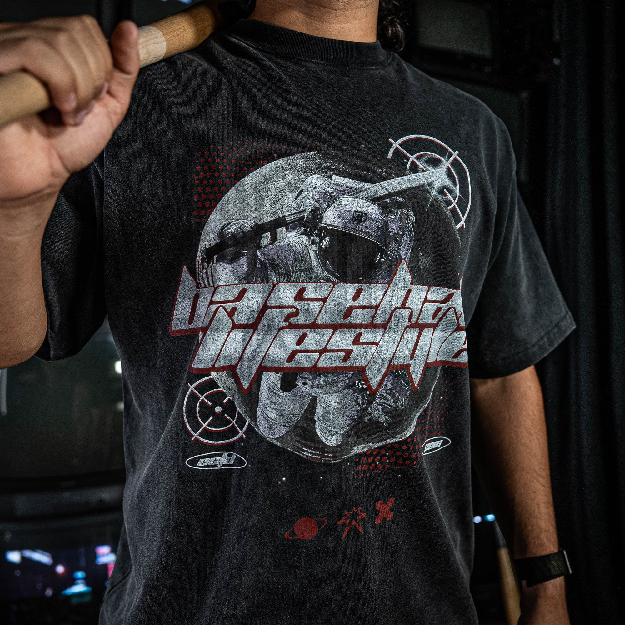 Person wearing a grey t-shirt with graphic design and 'Baseball Lifestyle' text, holding a bat
