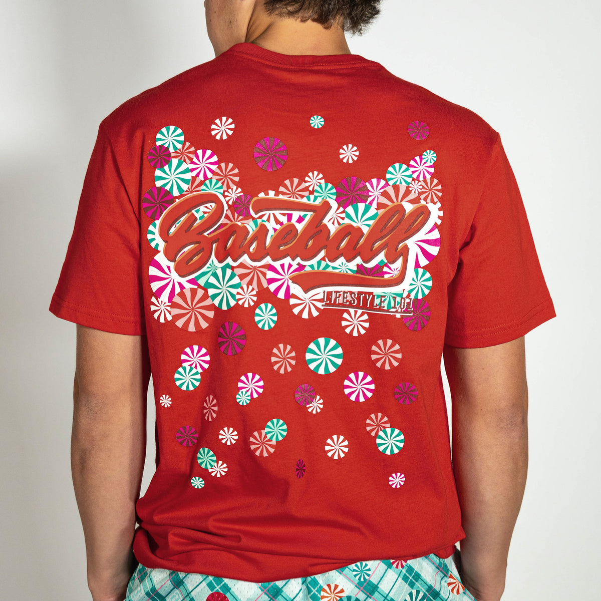 Adult model wearing red graphic tee with "Peppermint Plaid" design