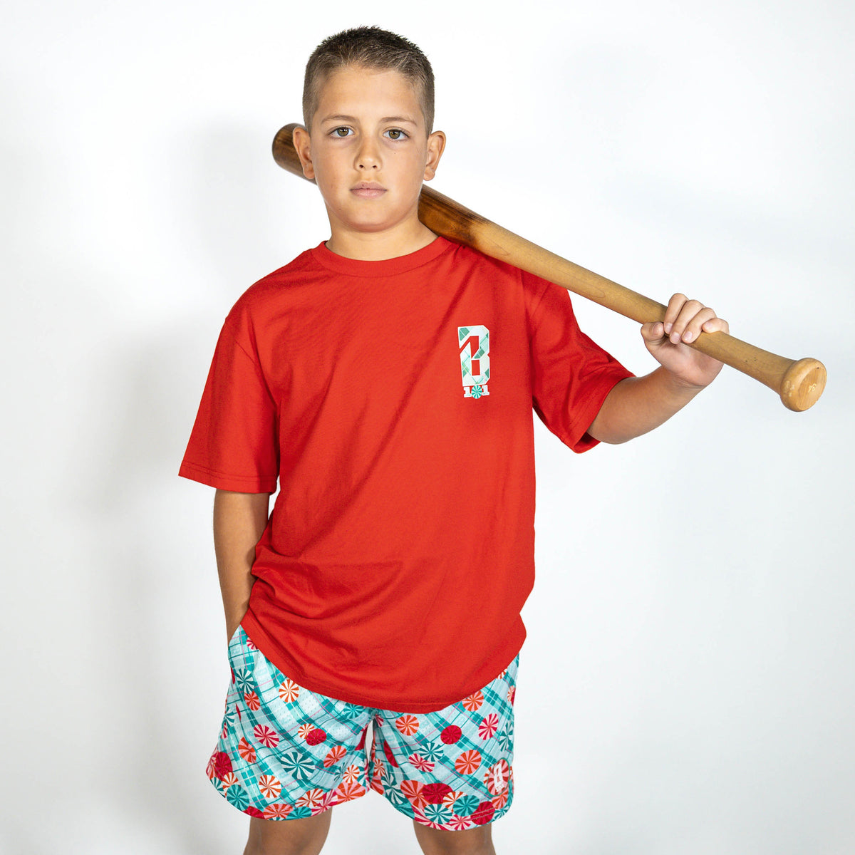Youth model wearing red youth graphic tee with "Peppermint Plaid" design