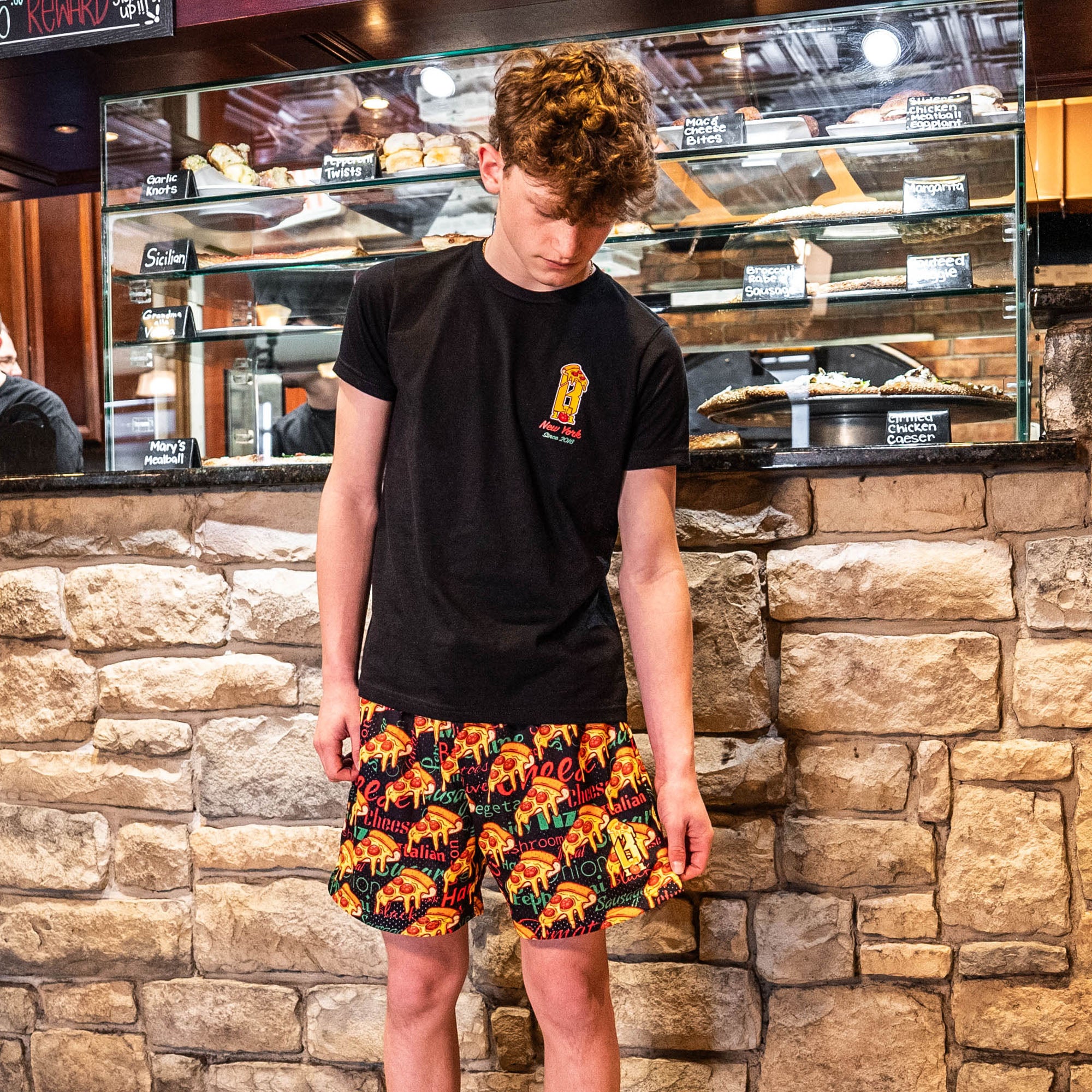 Youth model wearing black youth graphic tee with “Pizza Guy” design