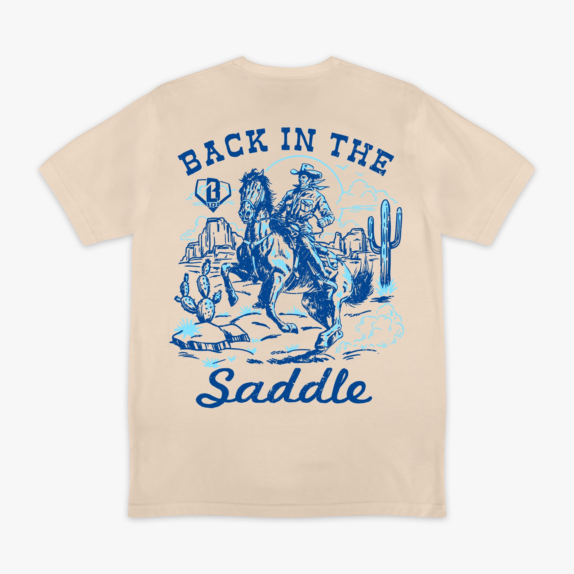 Beige t-shirt with blue graphic of a cowboy and text 'Back in the Saddle' on a white background