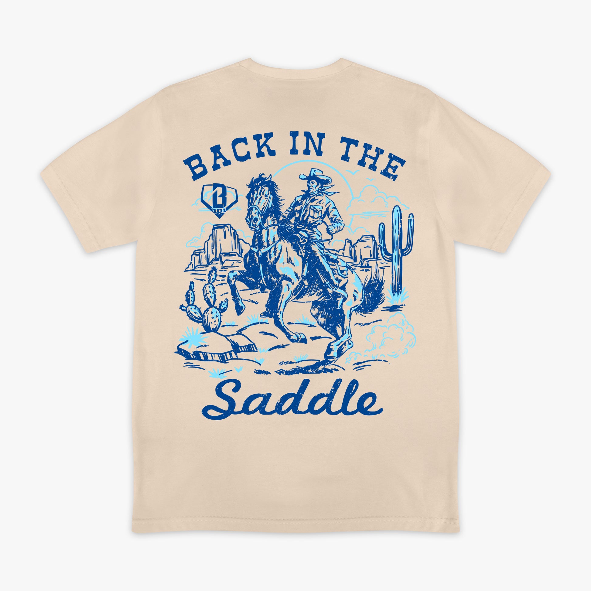 Beige t-shirt with blue graphic of a cowboy and text 'Back in the Saddle' on a white background