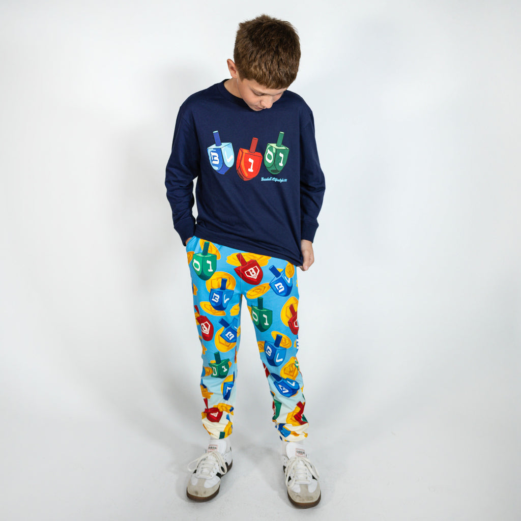 Youth model wearing navy youth graphic tee with "Spin & Swing Long Sleeve" design