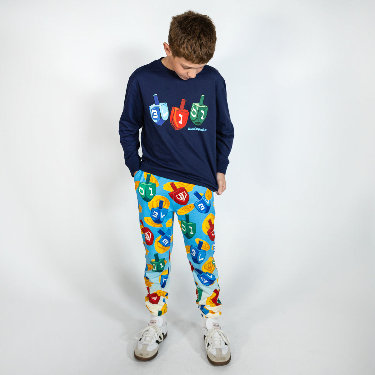 Youth model wearing navy youth graphic tee with "Spin & Swing Long Sleeve" design