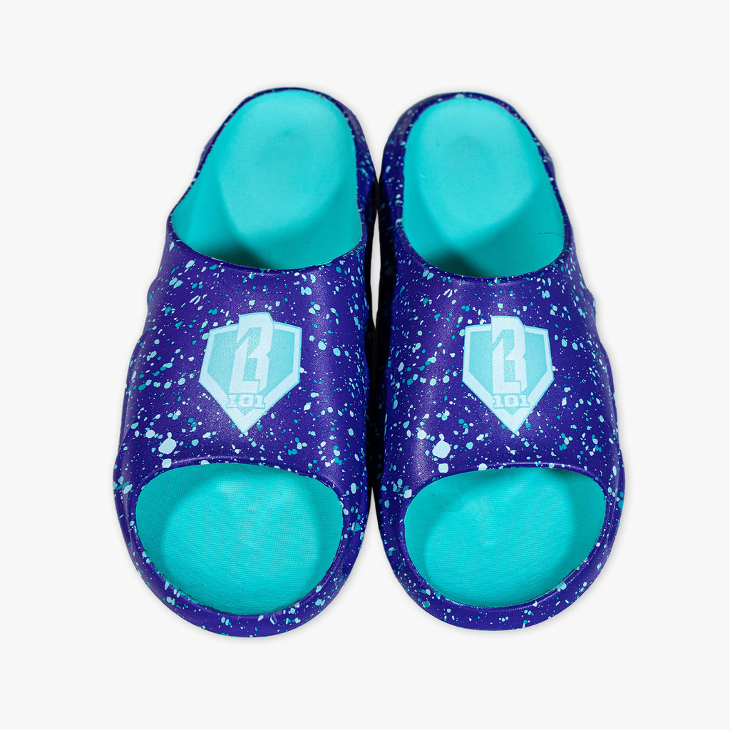 Top-down view of BL101 purple splatter slides with teal footbeds and teal home plate logo on a white background.
