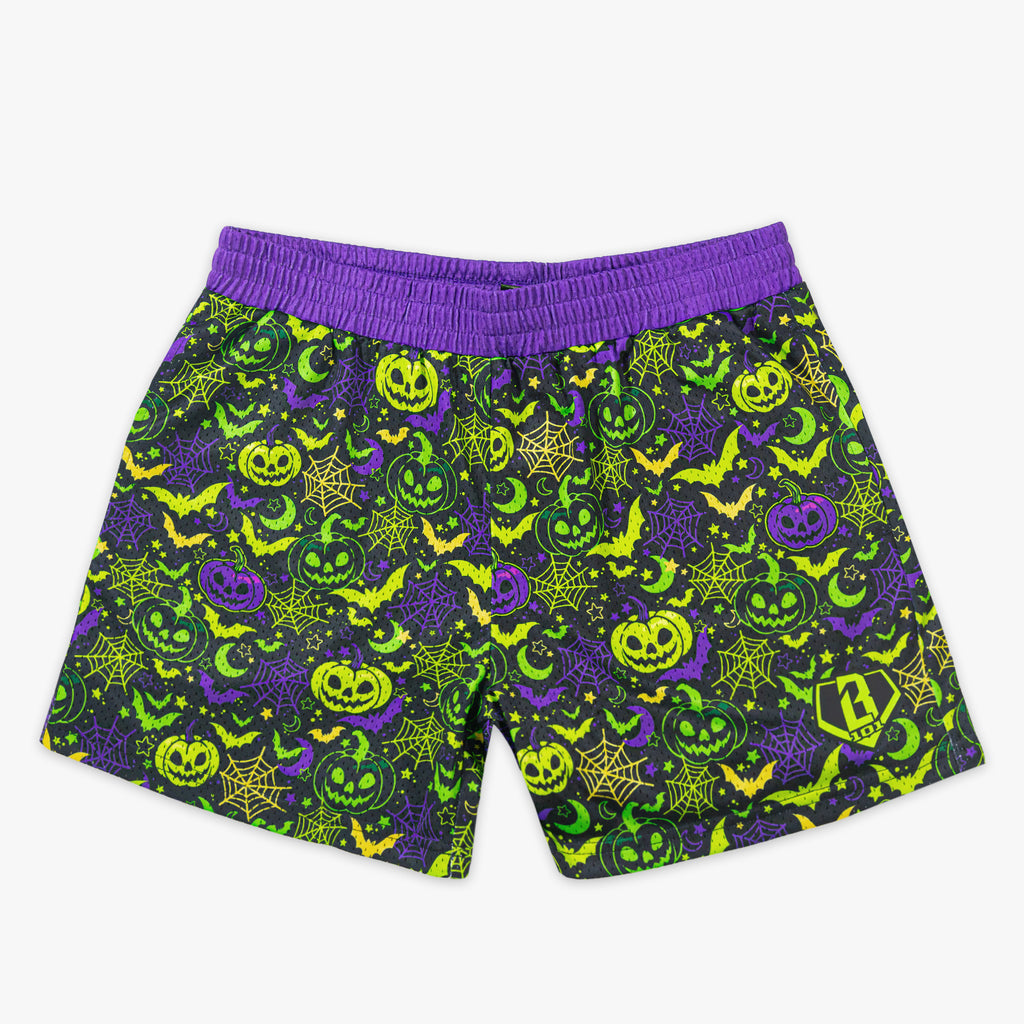 Purple and green halloween-themed shorts with pumpkins, ghosts, and bats on a white background