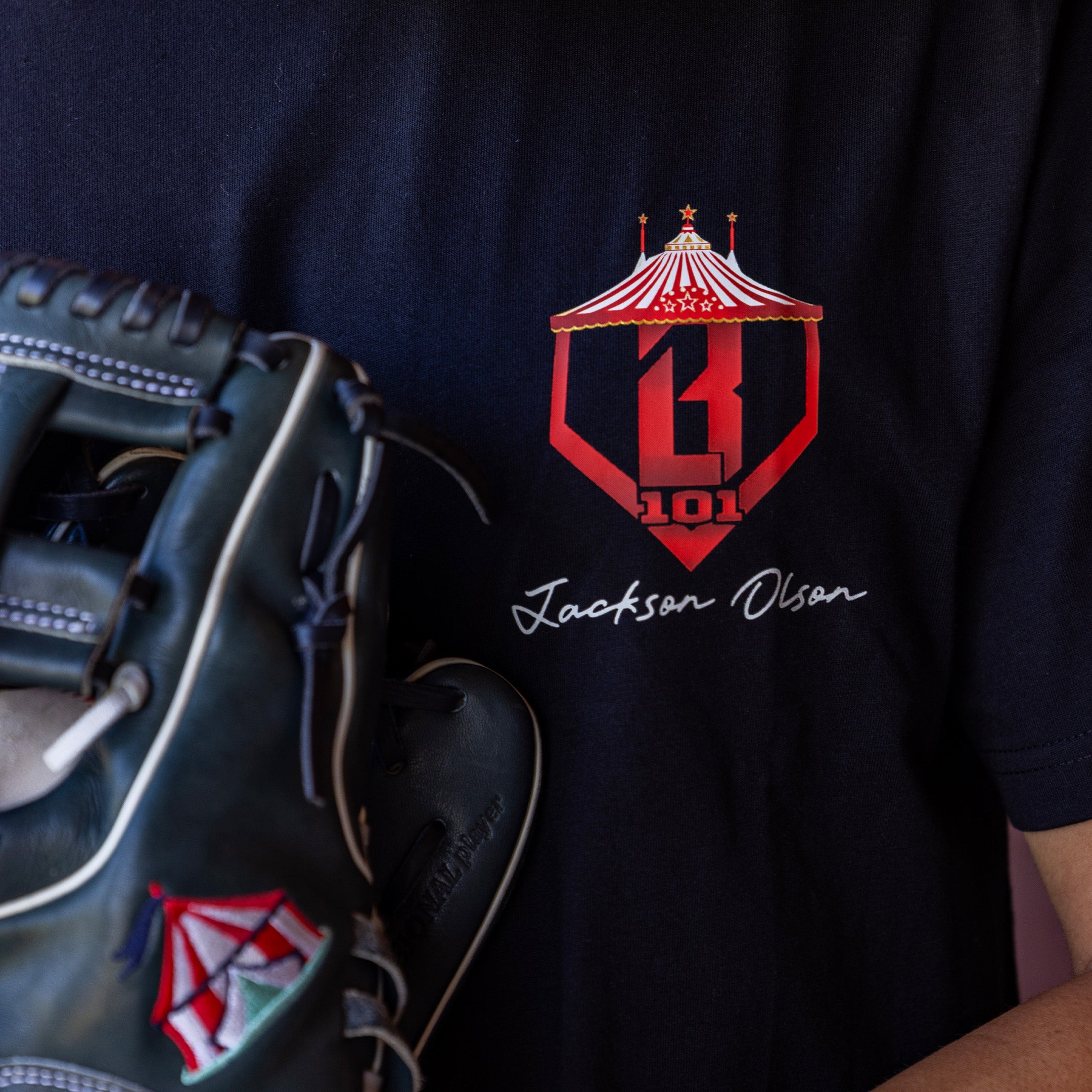 Black t-shirt with red and white BL101 logo and 'Jackson Olson' text, paired with a baseball glove.