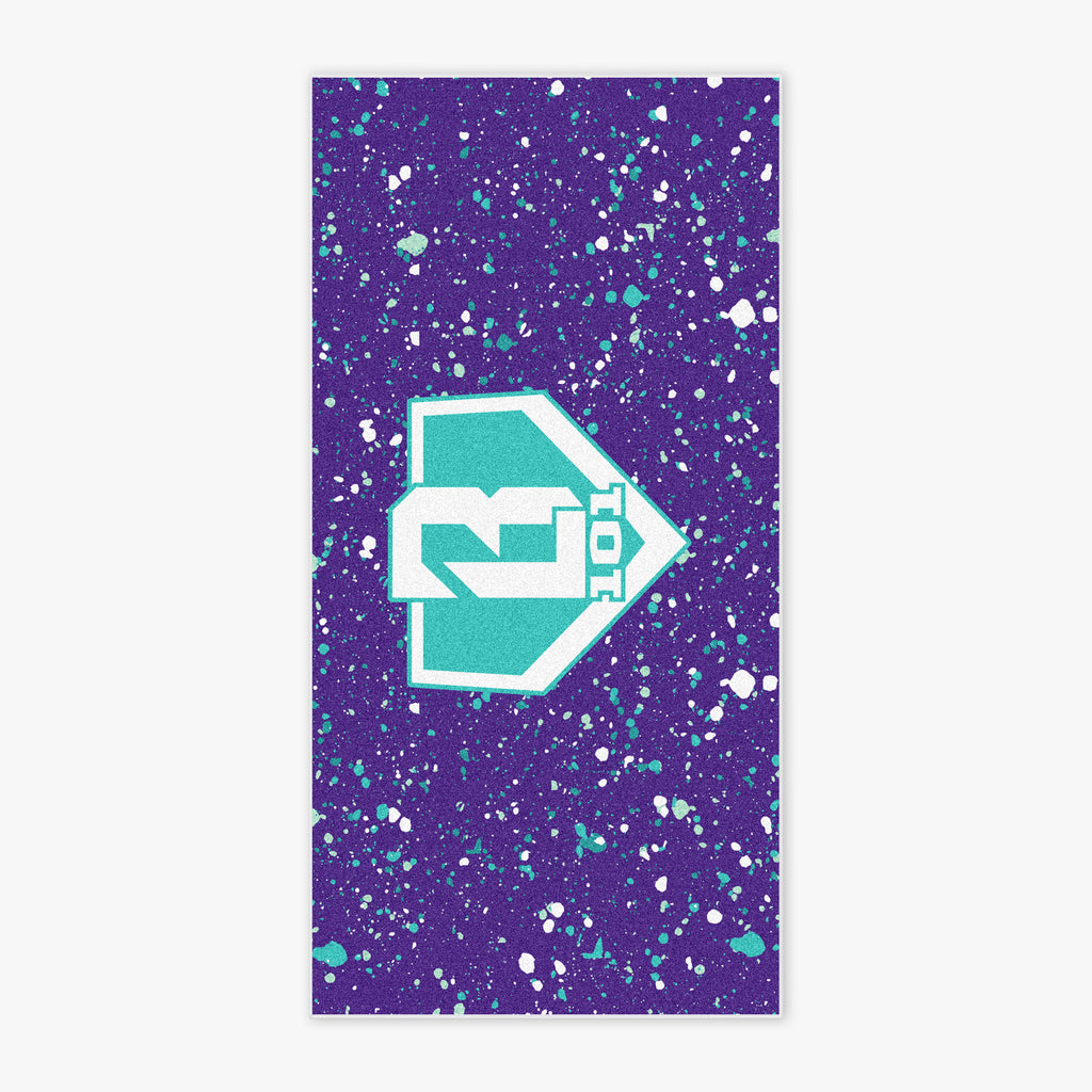 Flat lay of BL101 beach towel in purple with teal and white paint splatter and a bold teal BL101 logo in the center.