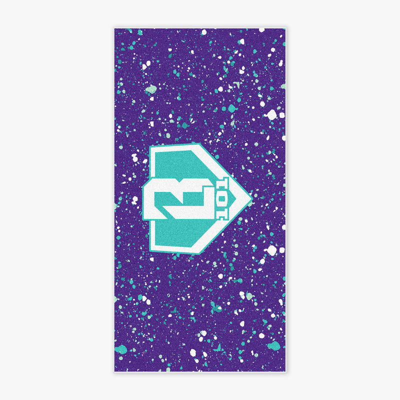 Flat lay of BL101 beach towel in purple with teal and white paint splatter and a bold teal BL101 logo in the center.