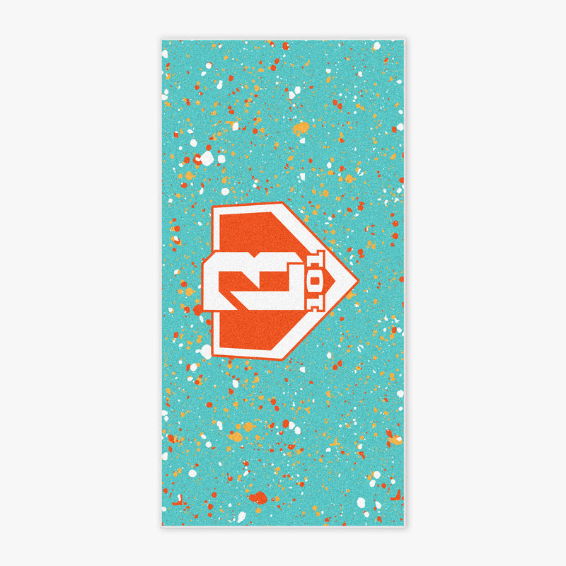 Flat lay of BL101 beach towel in teal with orange, red, and white paint splatter and a bold orange BL101 logo in the center.