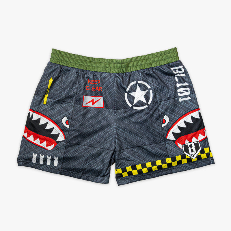 Military-inspired black athletic shorts featuring shark mouth graphics, a white star emblem, a red ‘Keep Clear’ detail, white BL101 logos on the sides, a green waistband, and yellow checkerboard trim.