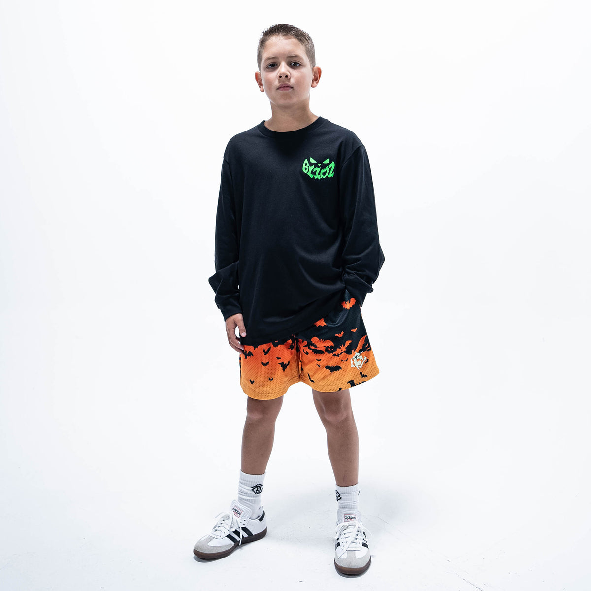 Youth model wearing orange youth shorts with "Bat Gradient" design