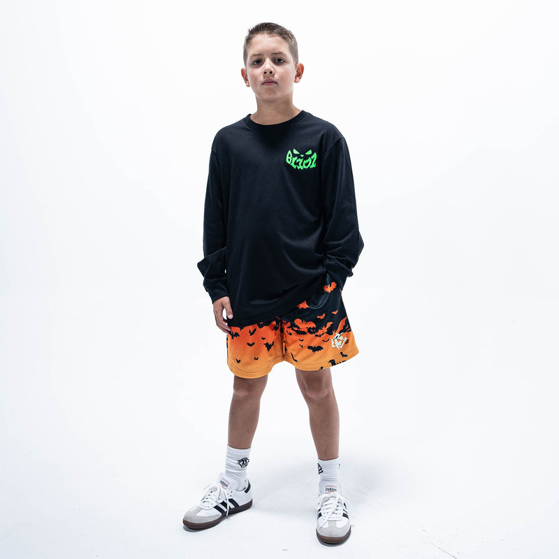 Youth model wearing orange youth shorts with "Bat Gradient" design