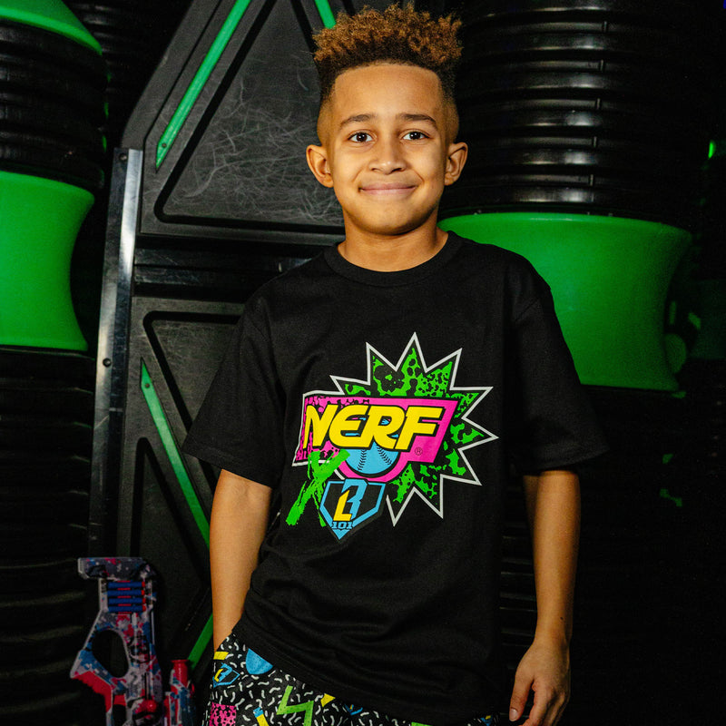 Child wearing a black t-shirt with a colorful 'NERF X BL101' logo in front of a green and black background.