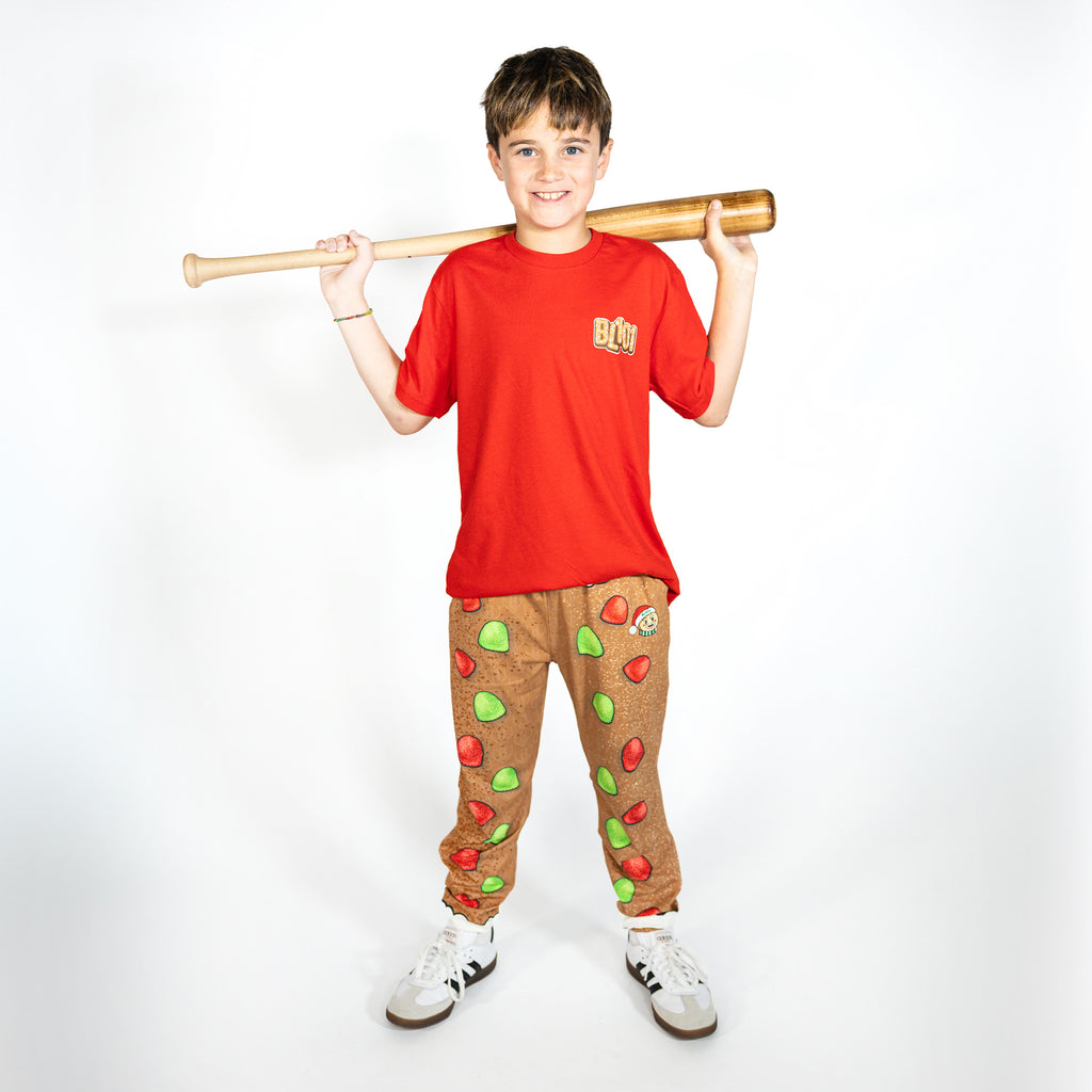 Youth model wearing brown youth pajama pants with "Gingerbread Rookie" design