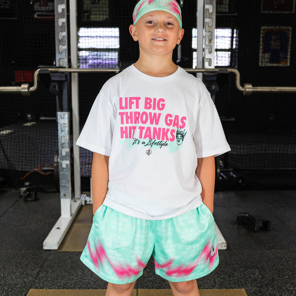 Youth model wearing teal shorts with "Hit Tanks" design
