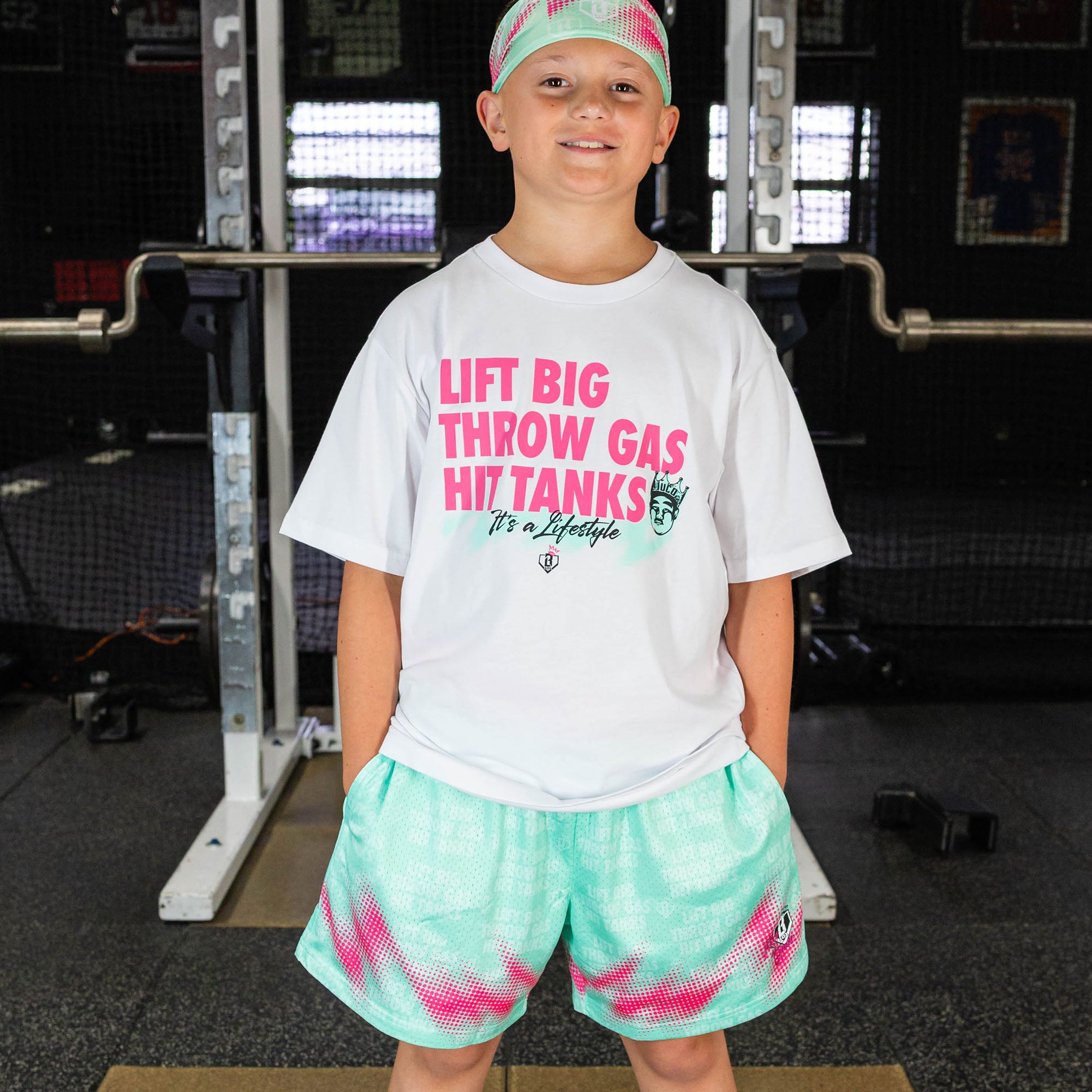 Youth model wearing teal shorts with "Hit Tanks" design