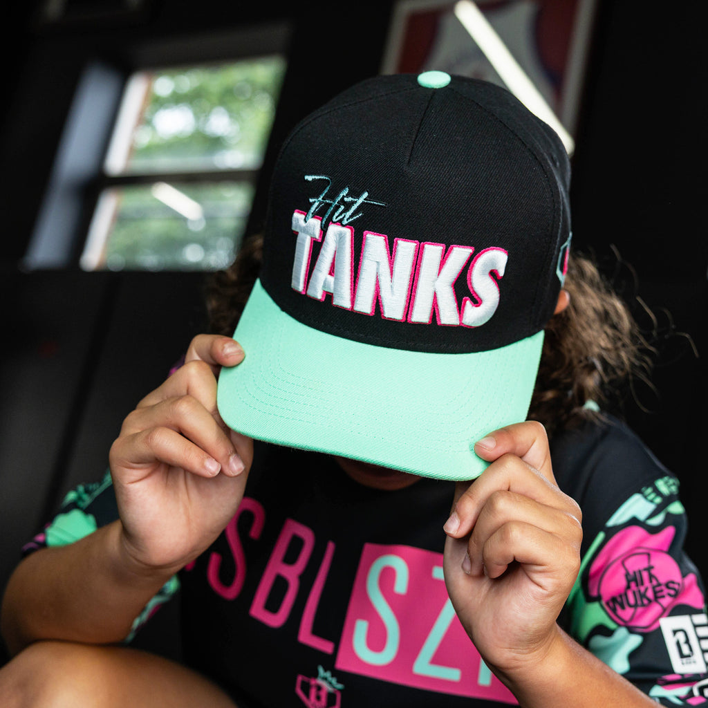 Youth model wearing black hat with "Hit Tanks" design