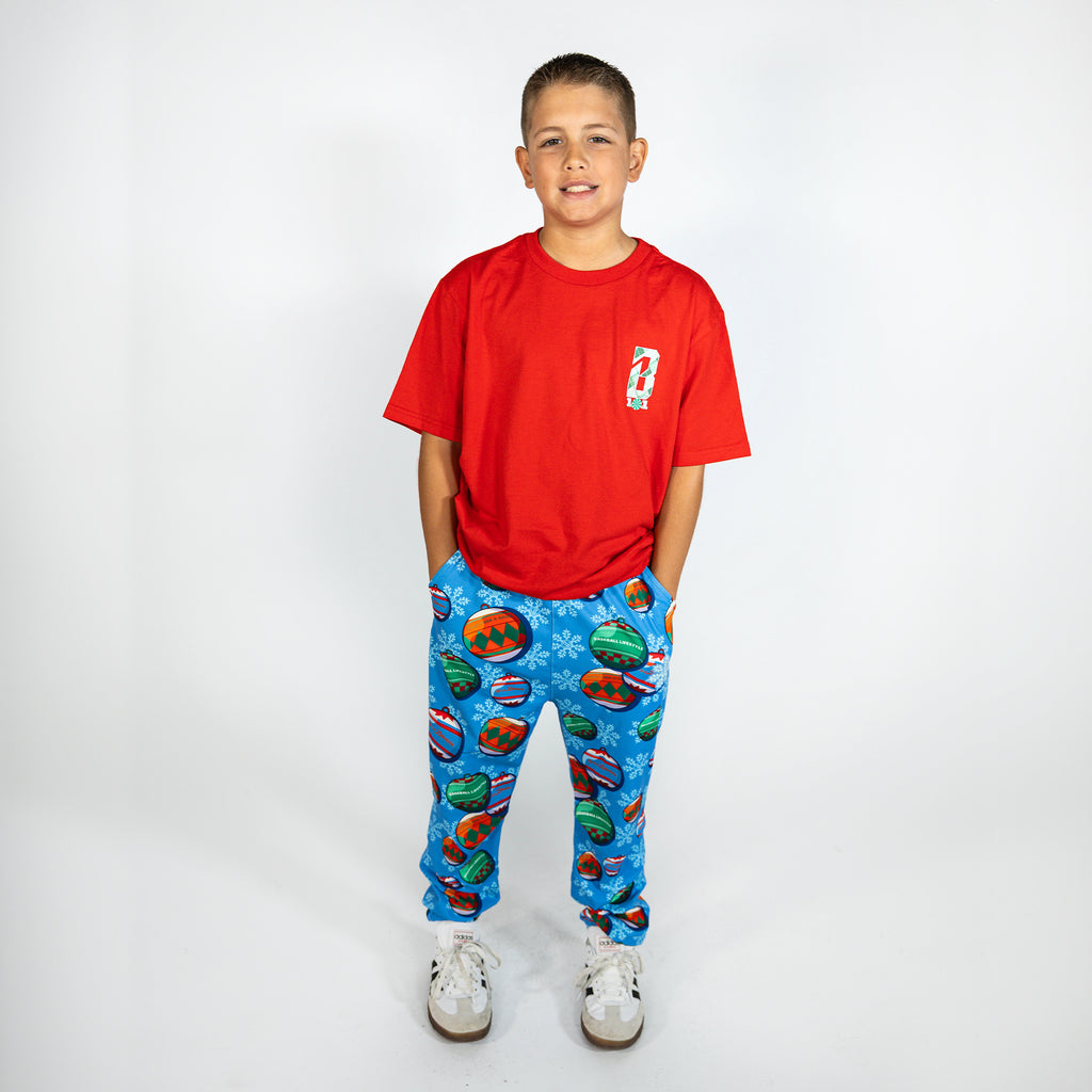 Youth model wearing blue youth pajama pants with "Jingle Ballers" design